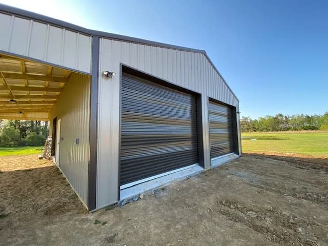 Exterior of finished farm shop buildout with closed roll-up doors, motion-sensor flood lights mounted under the awning